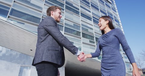 Business People Handshake - business people shaking hands. Handshake between man and woman outdoors by business building. Casual business clothing, young people in their 30s. SLOW MOTION