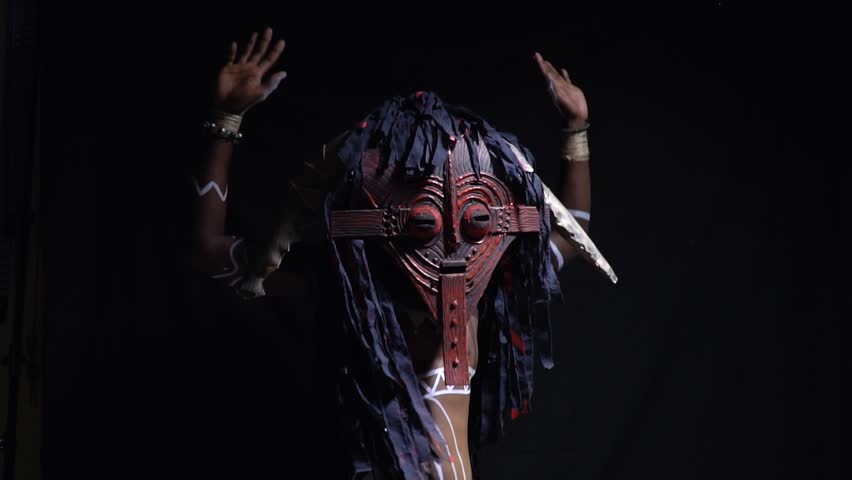 African man in ritual clothes and ornaments dancing on a black background, slow motion