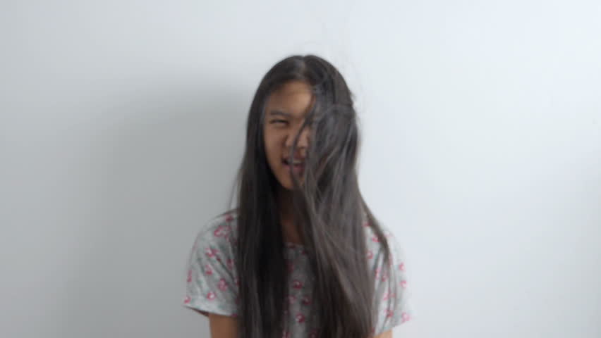 Slow motion shot of Happy Asian girl playing with hair blowing on white background