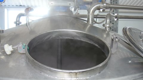 Freshly brewed hot beer foams in the brewing tank. Craft beer brewing. Steam