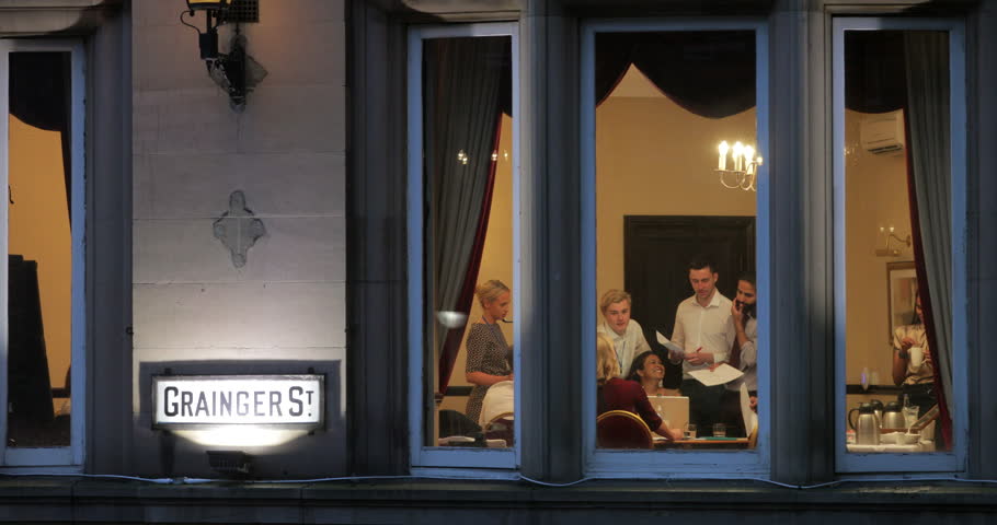 Through the window view of a group of business people working late in the office.