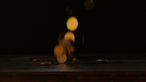 Coins falling to old wooden table bouncing rotating and landing in hd slow motion.
Coin falling down.