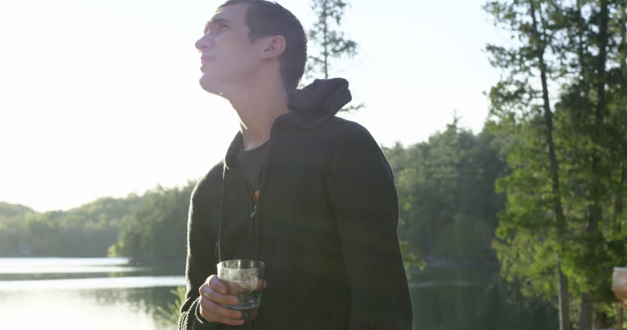 Young 20s man enjoying alcholic drink at cottage- looks around - slow motion