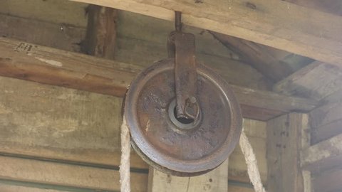 Old pulley in wooden water well house 4K video