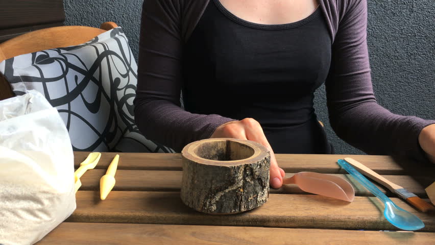 The woman florist pours a soil to a wooden flowerpot. close-up. front view	
