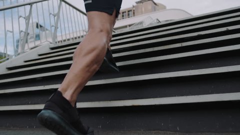 young man athlete legs running up stairs training intense cardio workout exercise male runner feet jogging on steps in urban city background slow motion