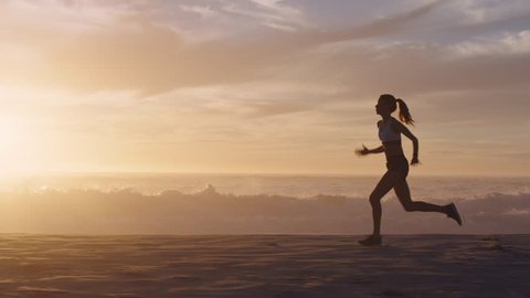 woman silhouette running on beach waves splashing female runner exercising sprinting intense workout on beautiful ocean seaside at sunset background