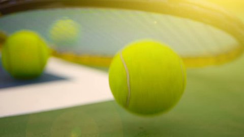 Close up of tennis equipment on the court. Sport, recreation concept. Yellow racket with a tennis ball in motion on a clay green blue court next to the white line with copy space and soft focus.