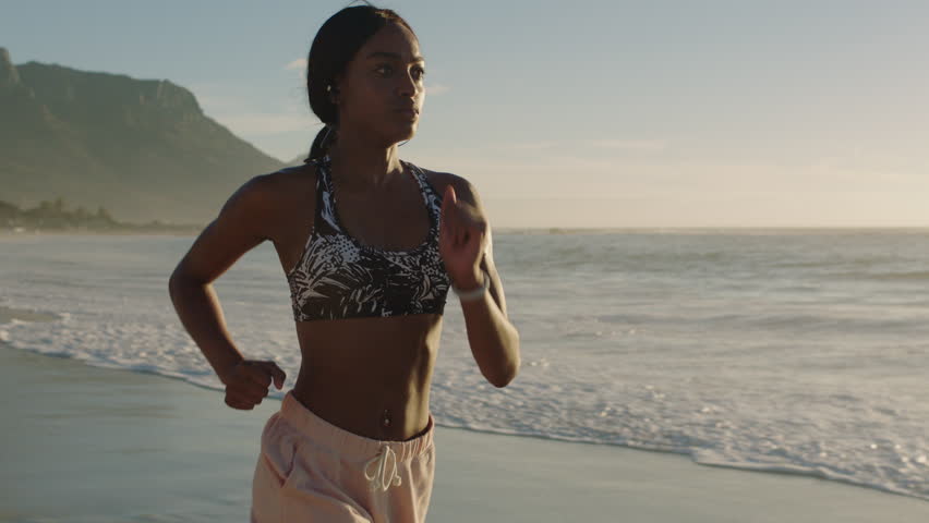 active young african american woman running intense fitness workout challenge training active fitness lifetyle on beautiful seaside beach sunset background