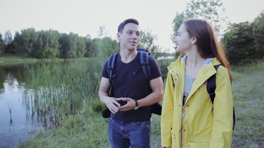 Man and woman tourists walking together along a river