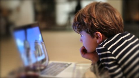 Child watching content on laptop screen. Kid hypnotized by cartoons watching media