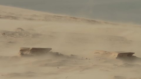 Sand storm in a desertic landscape with dunes. 'Lagoa da Conceição' and Joaquina's dunes.Telephoto lens shot (500mm). Fixed angle. Florianópolis, Santa Catarina / Brazil