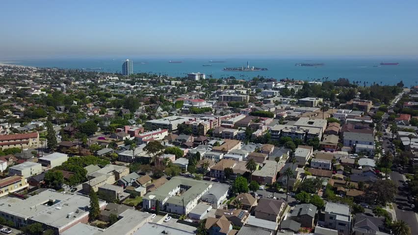 An aerial drone shot, slowly panning across a busy coastal desert city.