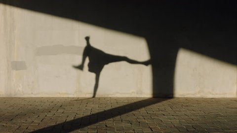 dancing man young street dancer breakdancing performing various freestyle dance moves fit mixed race male practicing in city at sunset with shadow on wall