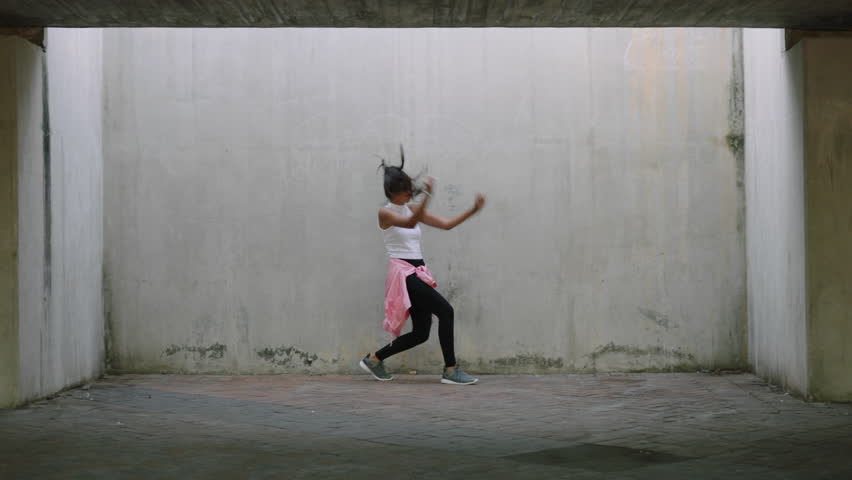 Dancing woman young mixed race street dancer performing freestyle hip hop moves enjoying modern dance expression practicing in grungy warehouse