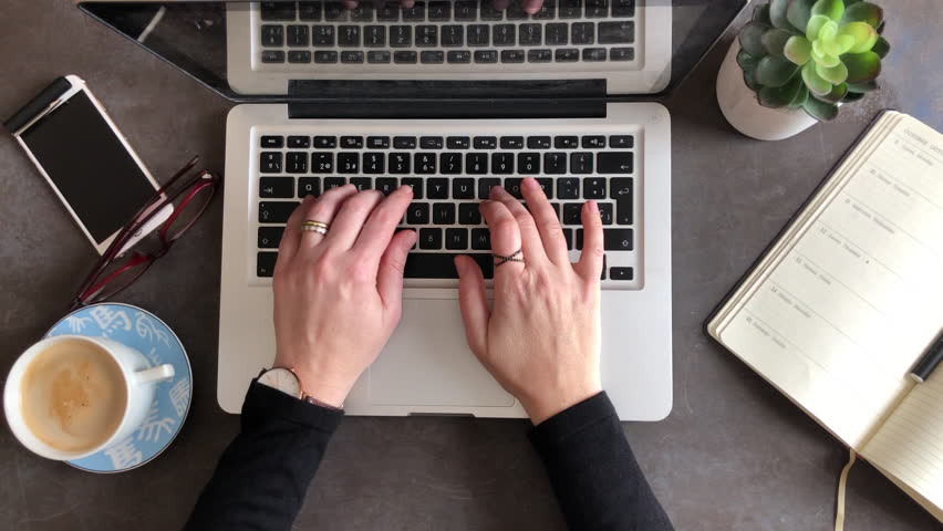 4K Top view of woman hands typing on computer. Smartphone, coffee, glasses and plant on desk Royalty-Free Stock Footage #1012946261