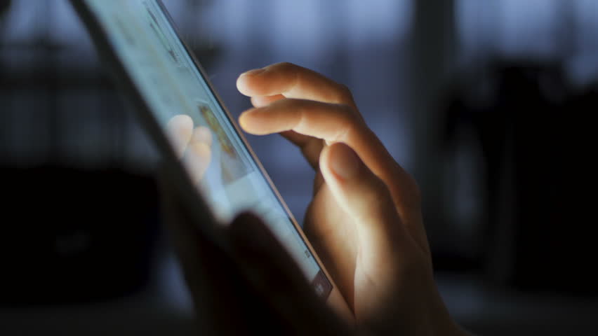 In this close up type of shot you can see young woman holding Apple Ipad touch screen tablet device in her hands. She is scrolling the screen while searching for pictures or reading news feed online.