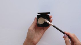 Woman hands hold brush and take green eyeshadow