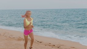 Beautiful sports blond woman running on the beach. 4k aerial video
