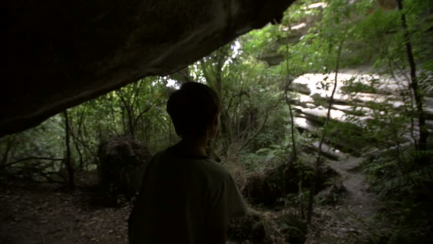 Silhouetted Young Boy Looking out of Cave