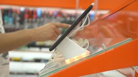 The buyer in the electronics store chooses a new gadget. 4k, close-up, blur background. Looking for a new peace of gadget.
