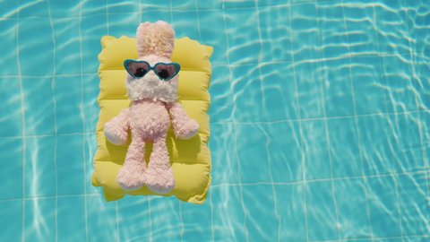 A cool rabbit in sun glasses glows on an inflatable mattress. Floats in the pool. Vacation with children