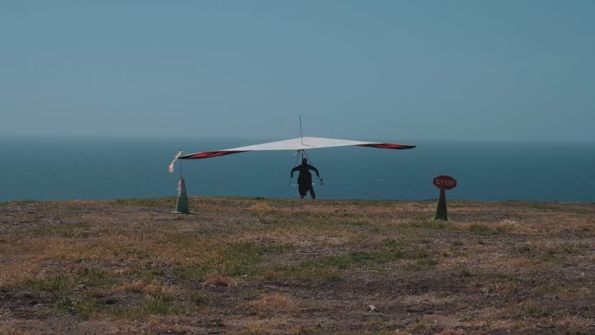 Hang glider taking off from a cliff in on California beach.