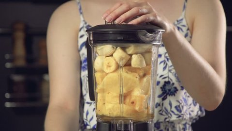 Closeup footage of female in summer dress mixing into blender pineapple and banana smoothie 