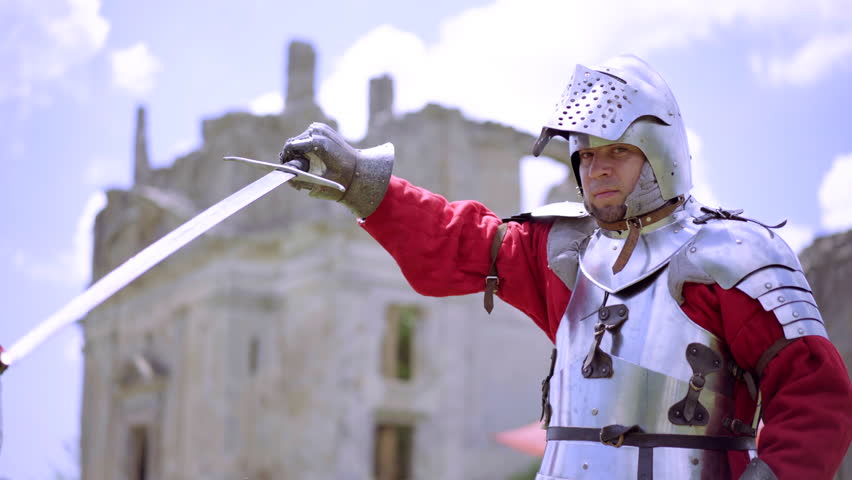 Portrait closeup of militant medieval knight wearing traditional steel armor and helmet, sword fighting. Fantasy and reenactment