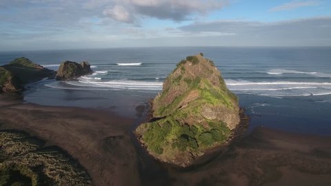 Aerial view of Lion Rock and large surf waves at Piha Beach, Auckland, New Zealand