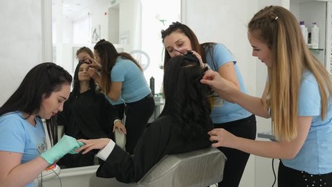 saving time, business woman doing manicure during make-up and hairstyles in beauty salon