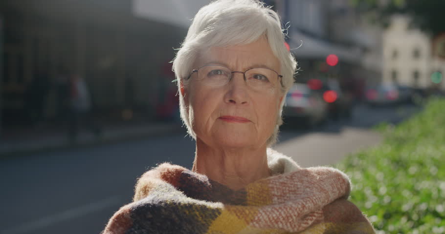 portrait of beautiful elderly woman looking calm pensive at camera wearing scarf middle aged caucasian female retirement age in urban city background real people series Royalty-Free Stock Footage #1012992392