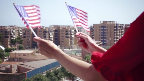 Red dressed woman waving USA national flag hand and celebrating a patriotic and american national holiday like 4th of July, Flag day, national day or memorial day.