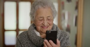 portrait of old woman using smartphone enjoying reading online messages senior woman watching video on mobile phone laughing happy in retirement home background