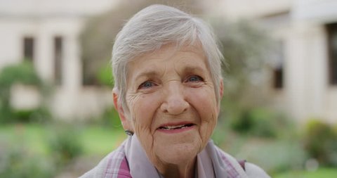 close up portrait of elderly caucasian woman smiling cheerful at camera enjoying sunny day in park happy retired