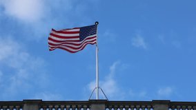USA Flag at Top of Building Pole Over Blue Sky