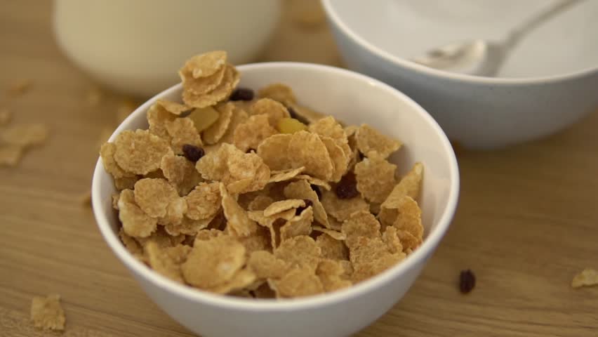 Healthy breakfast with flakes and dry fruits. Crispy Flakes falling down inside the plate, morning diet. Healthy vegeterian food coocked from high quality products .