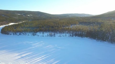 Aerial drone panoramic view of traditional houses, forest and fields in the snow in northern Norway. Cold sunny winter. 