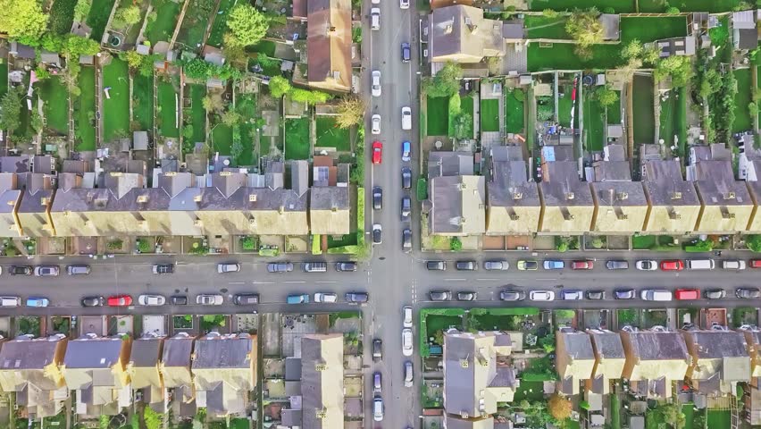 Aerial view of traditional British neighbourhood taken at sunset. Camera pans across the roofs of rows of old terraced houses. Royalty-Free Stock Footage #1013008757