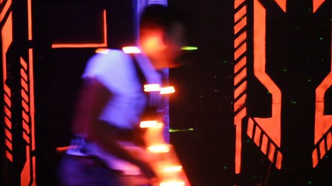 Group of young people with laser guns having fun on dark laser tag arena