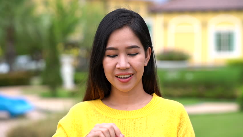 Happy asian woman blowing air bubbles in green garden with slow motion