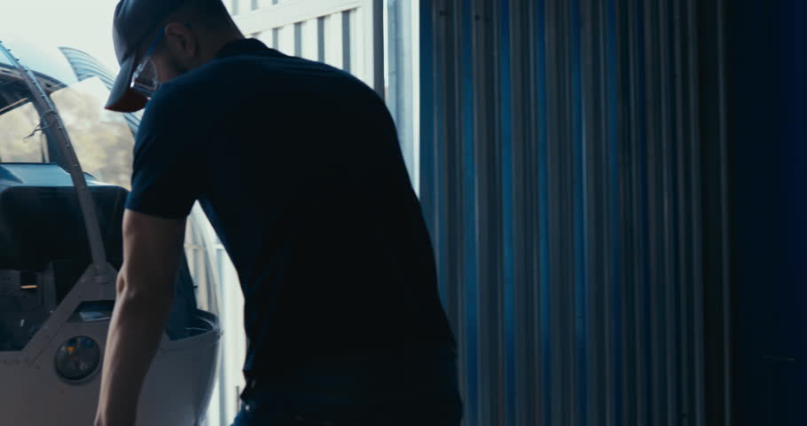 Male mechanic towing helicopter using tow cart, preparing for a flight. 4K UHD