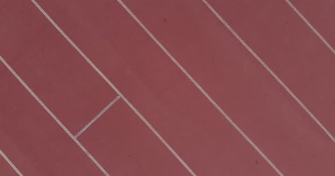 Aerial view of female runner listening to music and training by running on sports track