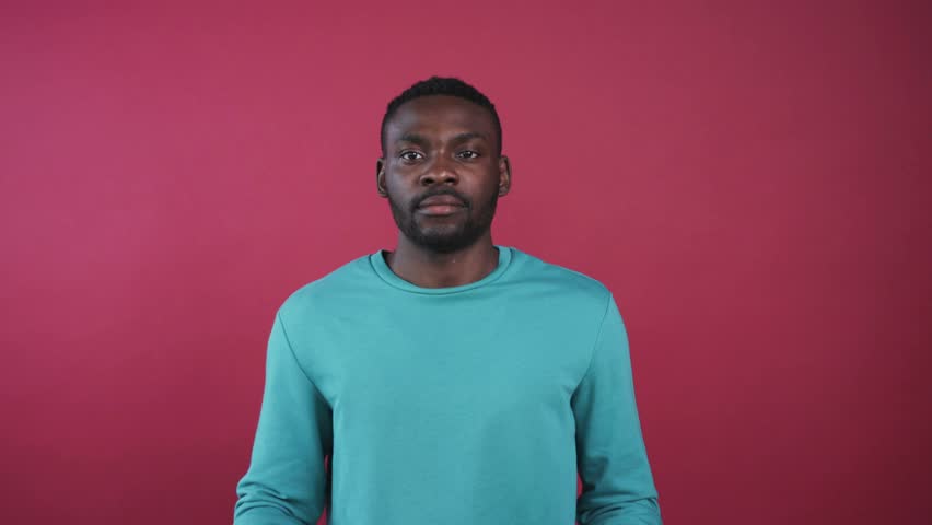 Likable African guy in beautiful mint sweater holding cake in hand, looking at camera. Attractive guy proposing cake on background of pink wall.