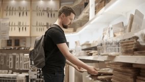 a young man chooses a culinary cutting board at a hardware store, he is going to cook and cut food on it at his work, maybe he's the chef - Powered by Shutterstock - Get 15% off with code: PIKWIZARD15