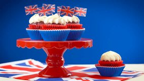Red white and blue theme cupcakes and cake stand with UK Union Jack flags for Queen's Birthday weekend celebration or Great Britain party food.