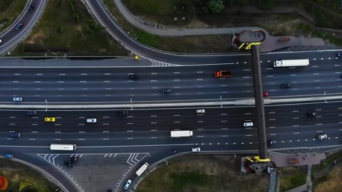 Aerial view of a motorway. Camera move left with a view on car interchange. A lot of cars ride on the 10 lanes motorway.