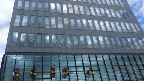 Window Washers Suspended from Ropes While Cleaning Windows on Tall Building, 4k footage. Gdynia, Poland - 19 July 2018