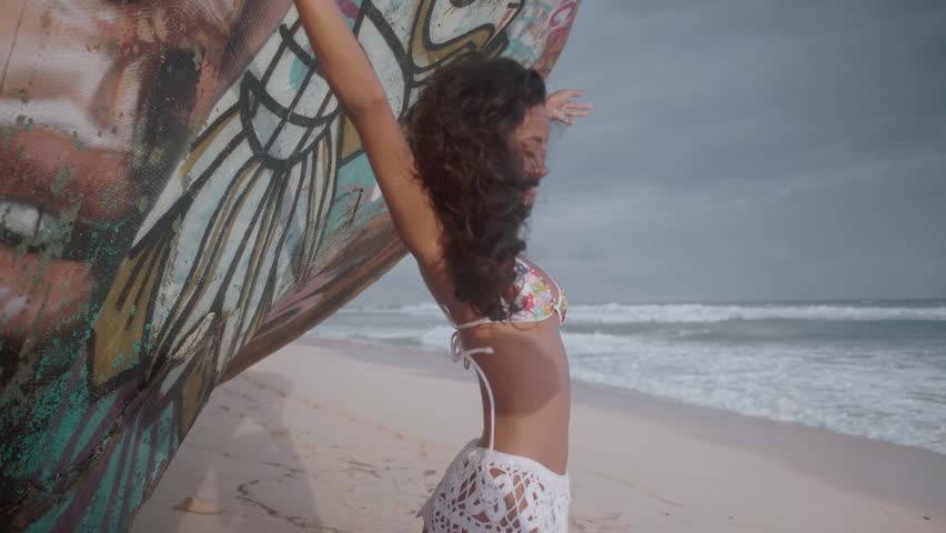Beautiful girl standing next to the shipwreck at the sandy beach during amazing sunset - video in slow motion