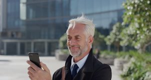 portrait happy mature businessman using smartphone video chat blow kiss enjoying conversation talking on mobile phone in sunny urban city slow motion long distance communication